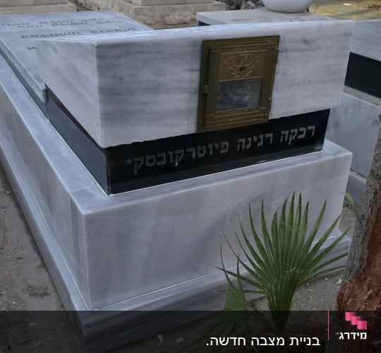 מצבת שיש מובנית עם בית נר וכיתוב על פס שחור